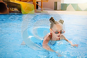 Cute little girl with inflatable ring in pool at water park