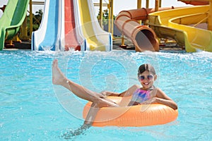 Cute little girl with inflatable ring in pool at water park