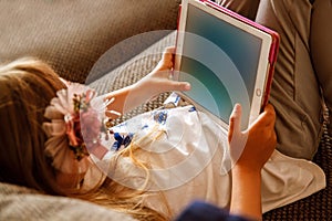 Cute girl kid using iPad digital computer tablet on bed for education or playing game. photo