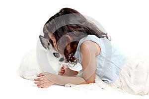 Cute little girl kissing rabbit while lying on floor. Joyful kid with her pet on white background. Happy child playing with her