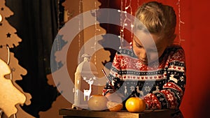 Cute little girl with a lantern writes a letter to Santa Claus on Christmas Eve in slow motion