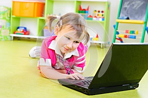 Cute little girl with laptop on floor
