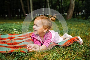 Cute little girl laughing on the grass looking up.