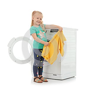 Cute little girl with laundry near washing machine