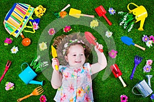 Cute little girl on a lawn with garden tools