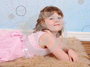 Cute little girl laying on a furry brown rug