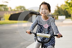 Cute little girl learning ride a bicycle with no helmet