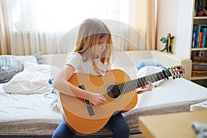 cute little girl learning to play teen guitar.