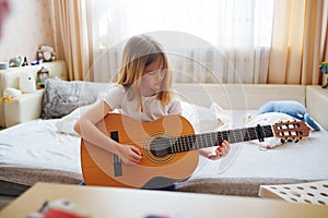cute little girl learning to play teen guitar.