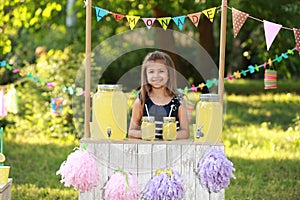 Cute little girl at lemonade stand in park. Summer refreshing natural