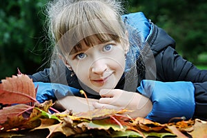 Cute little girl lie on the autumn leaves