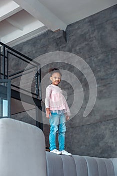 Cute little girl listening to music and dancing on sofa