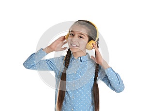 Cute little girl listening to music with headphones on white