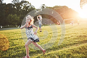 Cute little girl with long hair running with kite in the field on summer sunny day