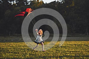 Cute little girl with long hair running with kite in the field on summer sunny day