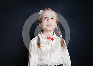 Cute little girl looking up on blackboard