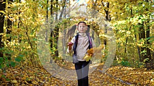 Cute little girl looks at camera and runs towards moving camera in autumn forest