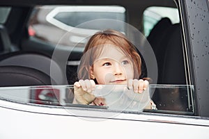 Cute little girl looks through window car. Conception of traveling and vaccation photo