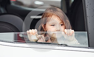 Cute little girl looks through window car. Conception of traveling and vaccation photo