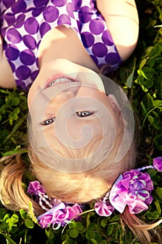 Cute little girl lying on the grass in the park. Smiling nice ch