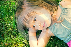 Cute little girl lying on green grass