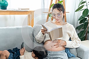 cute little girl Lying on her mother's lap, she was playing with her mobile phone, Asian single mother Sit and read book