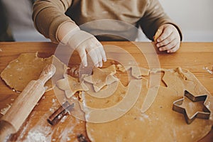 Cute little girl making christmas cookies on messy table, close up. Adorable toddler daughter helping mother and cutting dough for