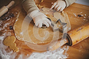 Cute little girl making christmas cookies on messy table, close up. Adorable toddler daughter helping mother and cutting dough for