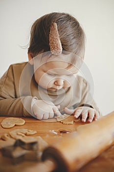 Cute little girl making christmas cookies on messy table, close up. Adorable toddler daughter helping mother and cutting dough for