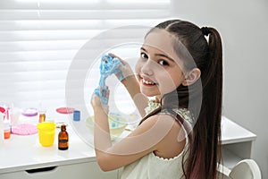 Cute little girl making DIY slime toy at table