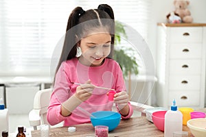 Cute little girl making homemade slime toy at table