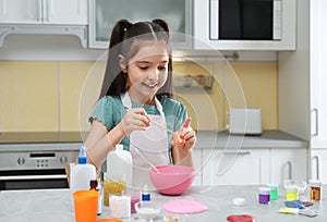 Cute little girl making homemade slime toy at table