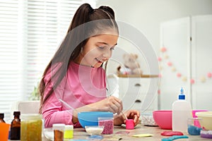 Cute little girl making homemade slime toy at table