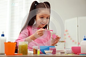 Cute little girl making homemade slime toy at table