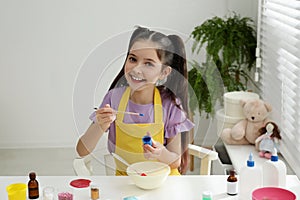 Cute little girl making homemade slime toy at table