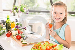 Cute little girl making salad. Child cooking. Healthy food