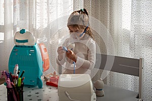 Cute little girl in the mask of an inhaler. Playing with toys. Procedure of inhalation at home. Kid taking respiratory therapy