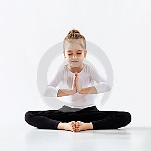 Cute little girl meditating in lotus position.