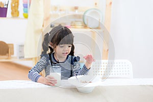 Cute little girl with milk mustache holding glass of milk