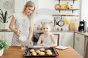 Cute little girl and mom eating freshly baked cookies with milk