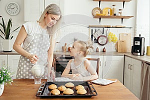 Cute little girl and mom eating freshly baked cookies with milk