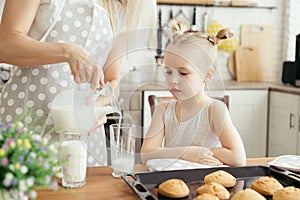 Cute little girl and mom eating freshly baked cookies with milk