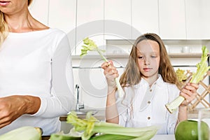 Cute little girl mother cooking healthy food celery apple kitchen home morning Healthy lifestyle concept