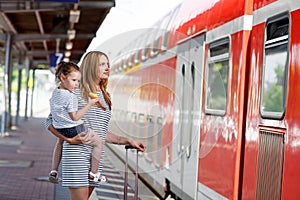 Cute little girl and mother on a railway station.