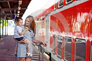 Cute little girl and mother on a railway station.