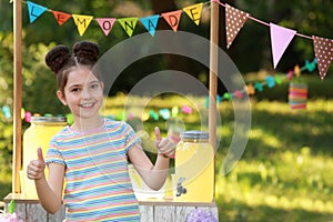 Cute little girl near lemonade stand in park. Summer refreshing natural drink