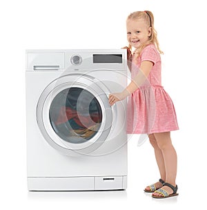 Cute little girl near washing machine with laundry