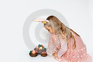 Cute little girl with nest with Easter eggs on white background. Adorable child celebrate Easter holiday