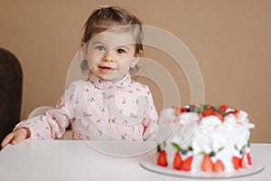 Cute little girl one and a hulf year old stand by delicious birthday cake. Eighteen month old girl verry happy and