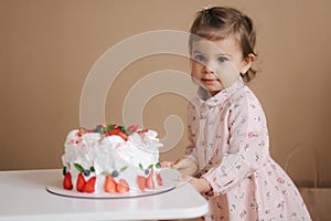 Cute little girl one and a hulf year old stand by delicious birthday cake. Eighteen month old girl verry happy and